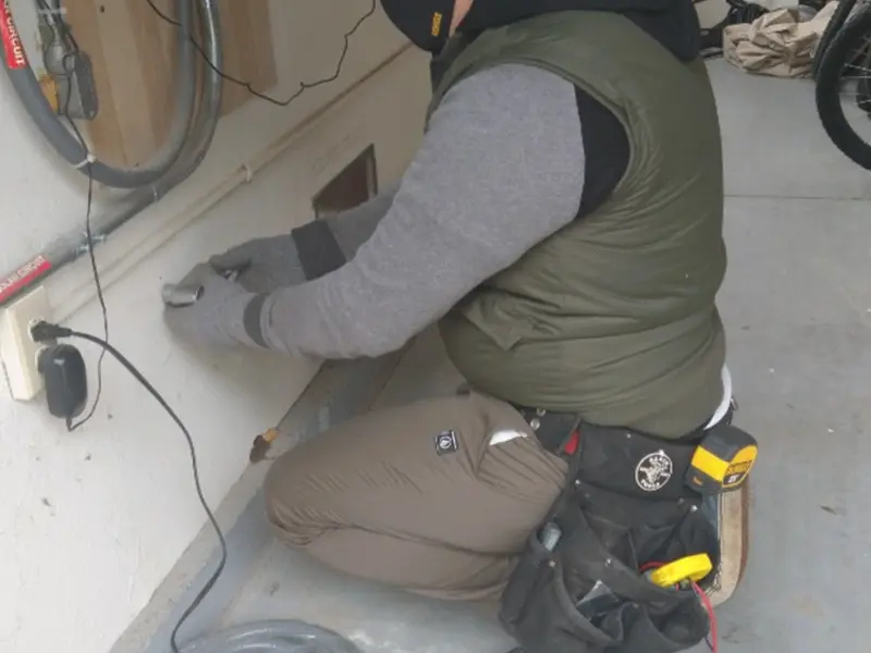 Electrician performing outlet wiring in a Cave Springs garage